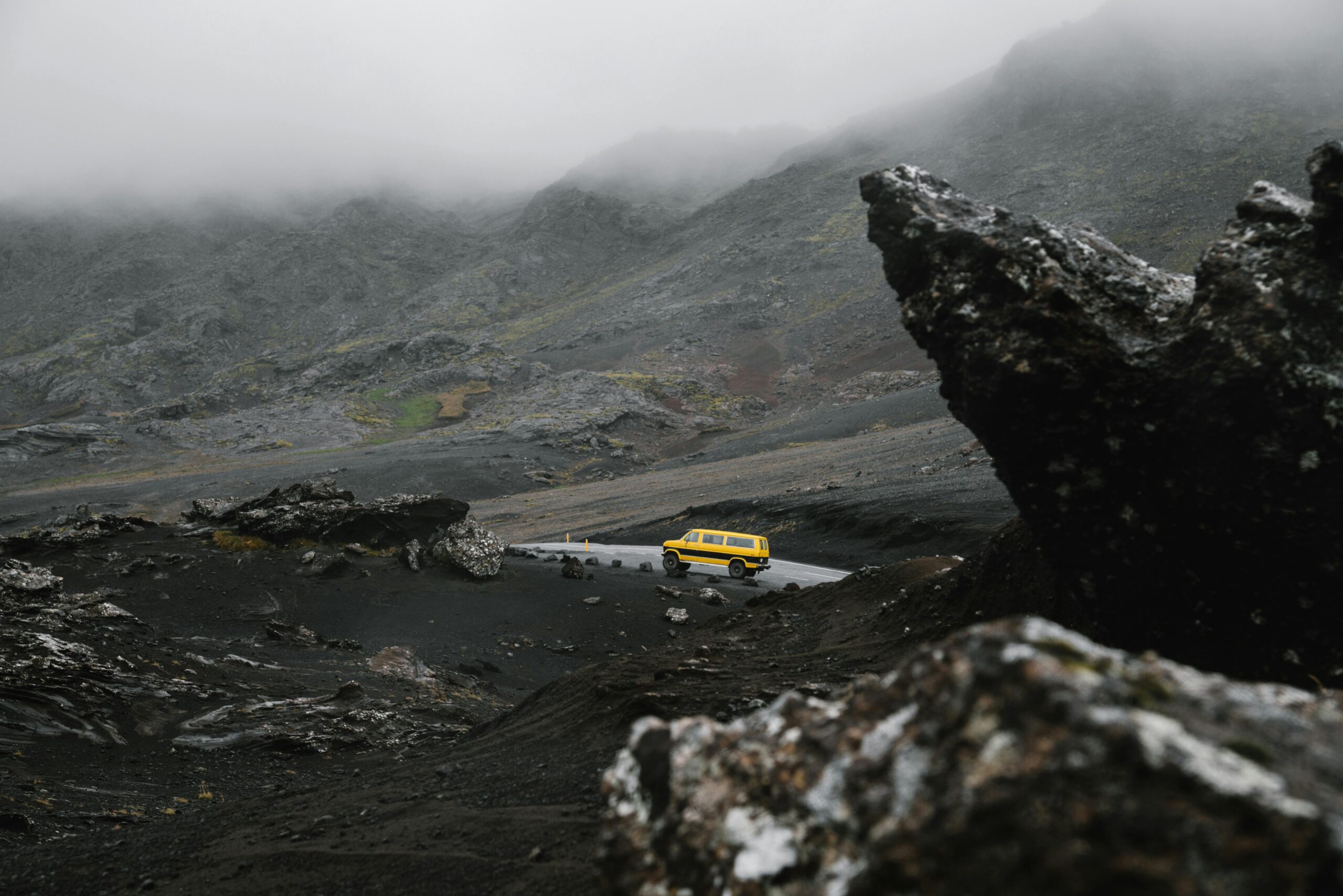 Car driving on road between ridge under overcast sky