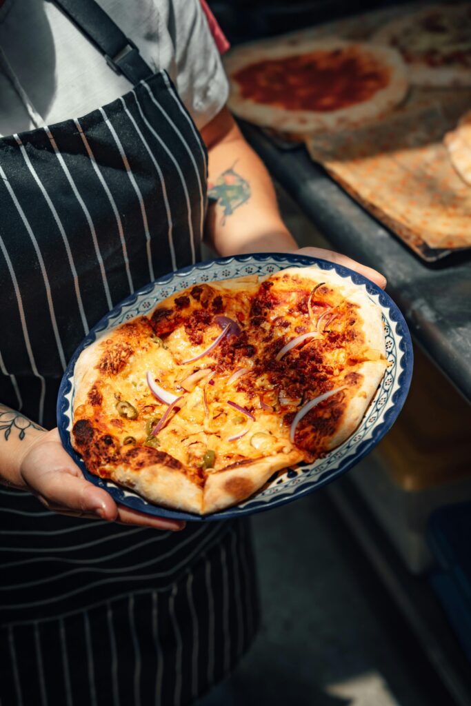 Woman in Apron Holding Delicious Pizza